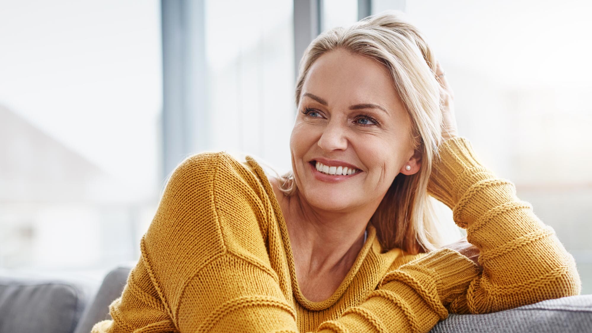 Auf dem Bild sitzt eine reife Frau entspannt auf dem Sofa. zahnarzt-muehlacker-ziegenhagel-iStock-1041507798.jpg